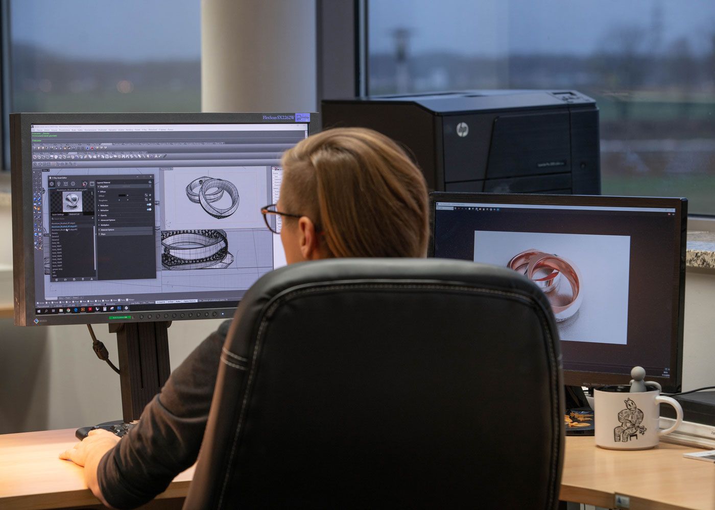Woman at her desk loopking at a computer with a CAD ring design on screen.